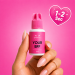 Hand holding a small pink bottle labeled 'Your BFF' against a pink background