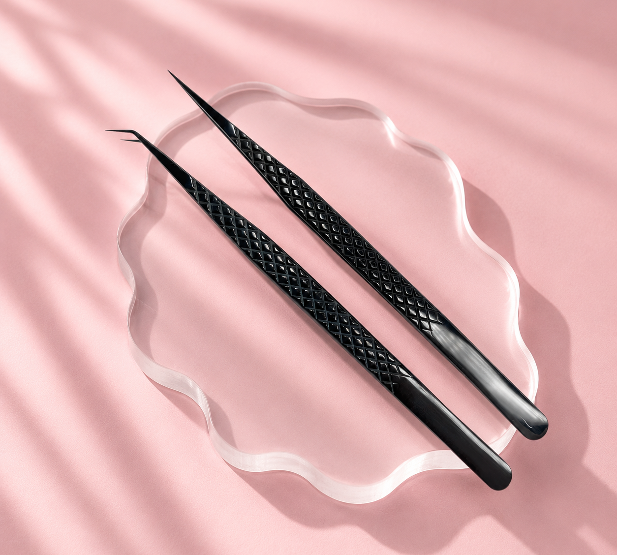 Two black tweezers on a pink fabric background