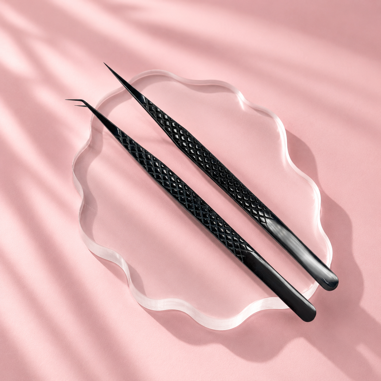 Two black tweezers on a pink fabric background