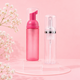 Pink foaming bottle and clear spray bottle on a pink background with white flowers.