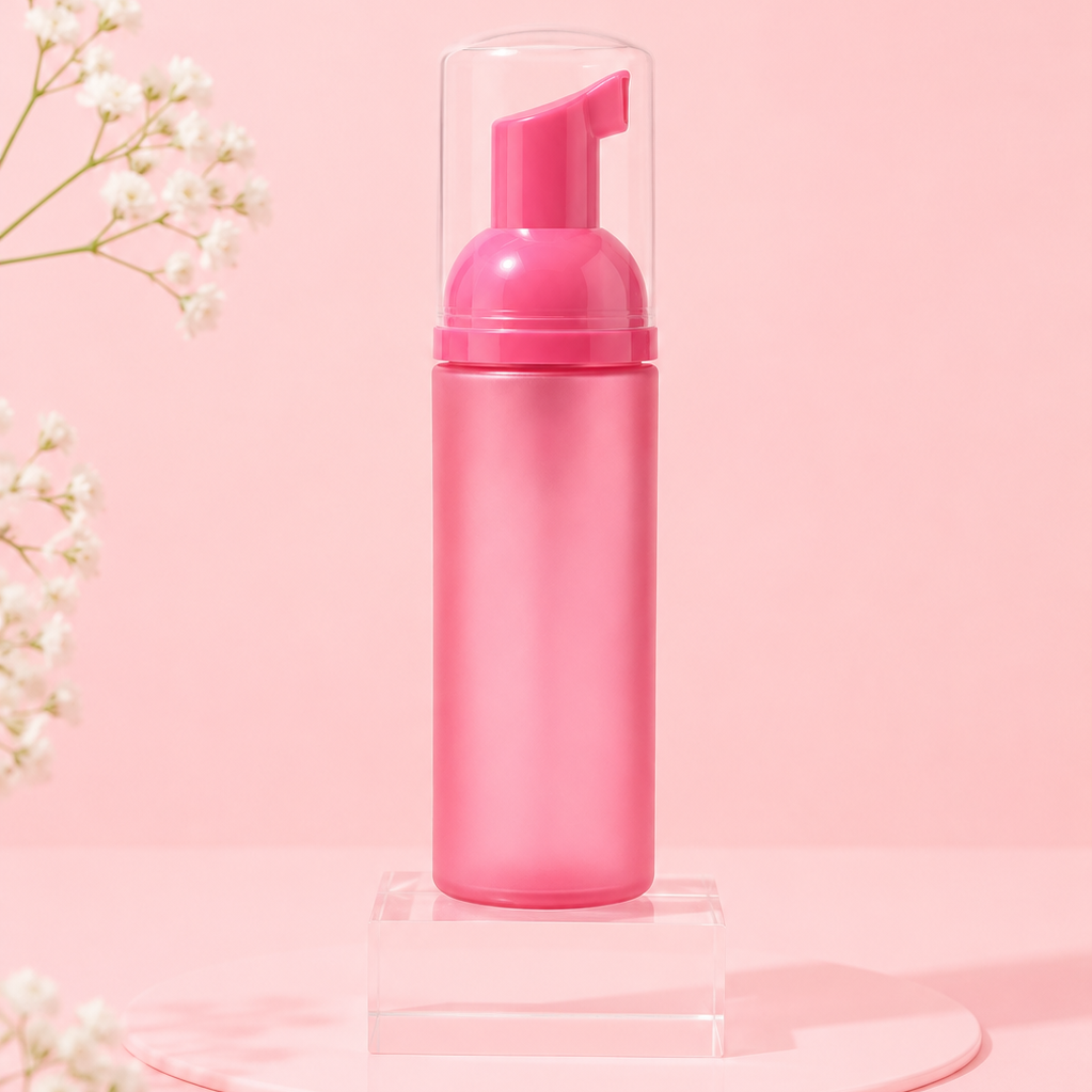 Pink foaming hand soap bottle on a pink background with white flowers.