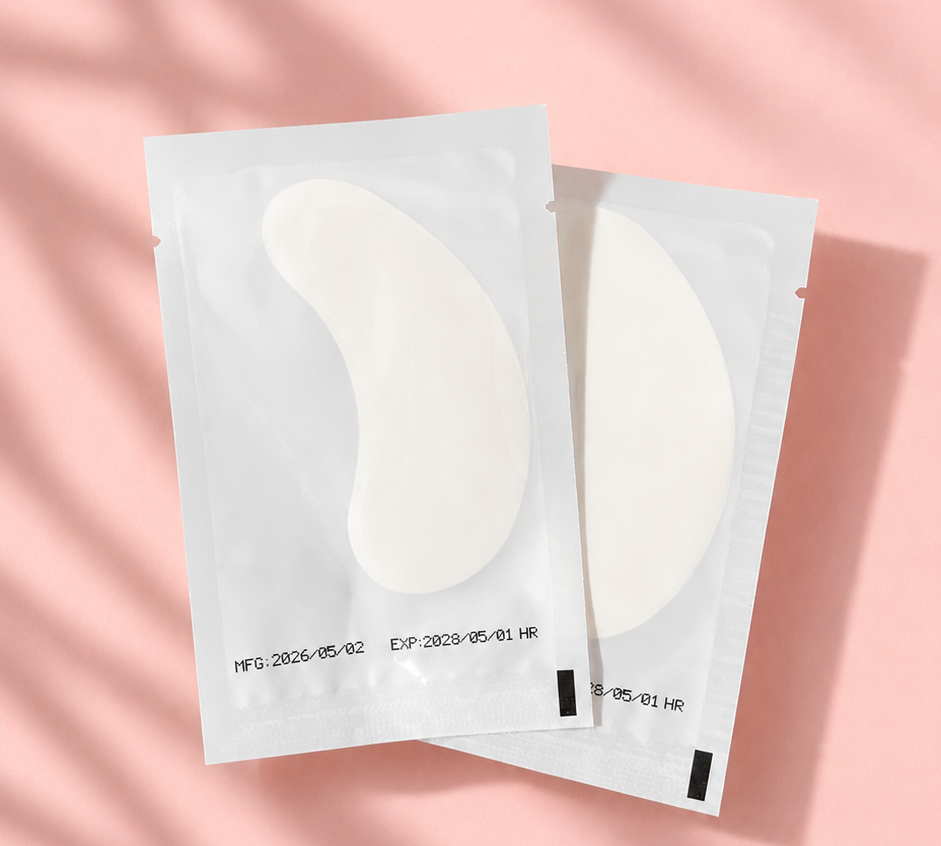 Two pairs of eye cream patches on a pink background