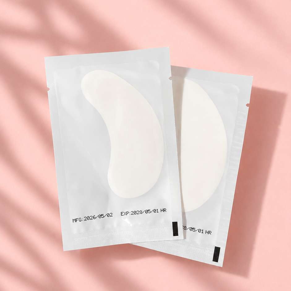 Two pairs of eye cream patches on a pink background